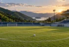 緑の山々と海を望む小さなサッカースタジアムの芝生、センターサークルに置かれたボール