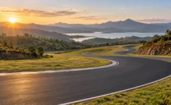 アフリカの丘陵地帯と湖を背景にカーブするサーキットのアスファルトコースのイメージ