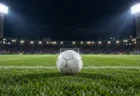 照明に照らされた夜のサッカースタジアムのピッチ中央に置かれた白いサッカーボール