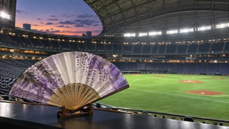 試合前のナイター球場のグラウンドと、手前に置かれた和柄の扇子