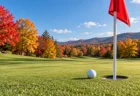 紅葉した木々に囲まれたゴルフ場のグリーンとピンフラッグ