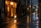 雨に濡れた夜の路地に、提灯と行灯の明かりがともる小さな店の入口