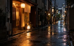 雨に濡れた夜の路地に、提灯と行灯の明かりがともる小さな店の入口