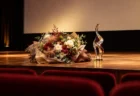 映画館のスクリーン前の舞台に置かれた花束とトロフィー