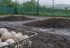 雨上がりの高校野球のブルペンに置かれた、白い硬式ボールが入ったかご