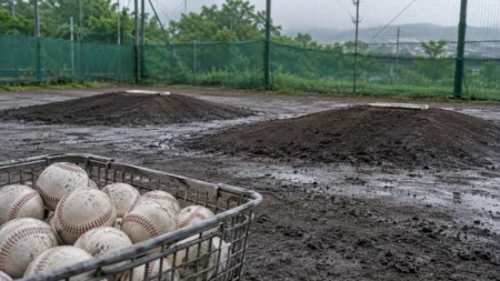 雨上がりの高校野球のブルペンに置かれた、白い硬式ボールが入ったかご