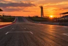 夕方のサーキット、上り坂の1コーナーへ続く広いアスファルトの直線と空のグリッド枠