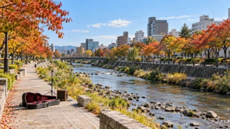 秋の札幌の川沿いの公園の遊歩道に置かれたアコースティックギターとマイクスタンド