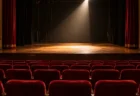 開演前の劇場の舞台を照らすスポットライトと赤い客席