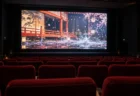 照明が落ちた映画館の無人の赤い座席と、和風の舞台が映る大きなスクリーン