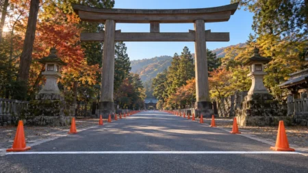 秋の朝、神社の大きな鳥居の前から伸びる道路に白いスタートラインとコーンが並ぶ風景
