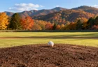 紅葉した山を背にした野球場のマウンドに置かれた白い硬式球