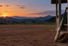 夕暮れの地方球場の内野グラウンドとベンチ前に置かれたバットとグラブ