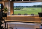 照明が落ち着いたテレビスタジオの無人のデスクとモニター