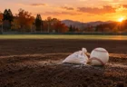 秋の夕方の球場で、マウンドに置かれたロジンバッグと白い硬式球