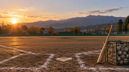 秋の夕方の高校野球グラウンドに置かれたノックバットとボールかご