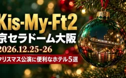 Kis-My-Ft2 京セラドーム大阪 2026.12.25-26 クリスマス公演に便利なホテル5選の文字と、モミの枝に下がる緑のガラスのオーナメントに夜の街と電車が映り込む写真風の画像