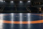 照明に照らされた無人のレスリングマットと観客席
