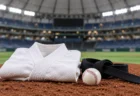 照明に照らされた屋内球場のマウンドに置かれた、たたんだ白い柔道着と黒帯、硬式の野球ボール