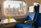 朝の新幹線の車内、窓側と通路側の座席が並び窓の外を都市の景色が流れる
