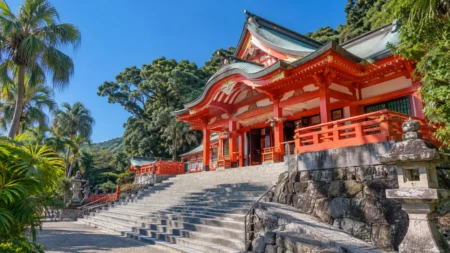 晴れた青空の下、朱塗りの神社社殿と石段