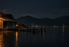 夜の地方都市の湖畔に立つ古いボートハウスと水面に映る街灯