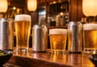 木のカウンターに並ぶビールの缶とグラス