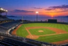 球場のスタンドから見た夕暮れのグラウンドと照明