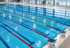 照明に照らされた屋内プールの水面とレーンロープ