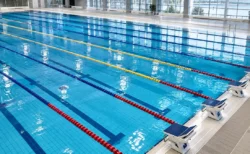 照明に照らされた屋内プールの水面とレーンロープ