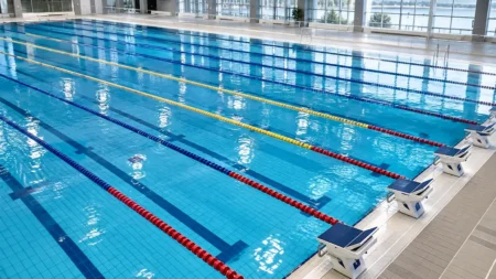 照明に照らされた屋内プールの水面とレーンロープ