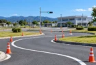 晴れた日の自動車教習所のS字カーブに並ぶパイロンと、奥の信号機と校舎