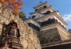 秋晴れの小倉城天守閣と石垣の脇に置かれた戦国時代の甲冑