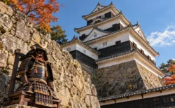 秋晴れの小倉城天守閣と石垣の脇に置かれた戦国時代の甲冑