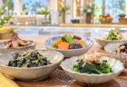 明るいキッチンスタジオの調理台に並ぶ、野菜の和え物や煮物の小鉢料理のイメージ