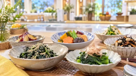 明るいキッチンスタジオの調理台に並ぶ、野菜の和え物や煮物の小鉢料理のイメージ