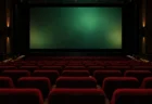暗転直前の映画館の大スクリーンと、後方席から見た空席の赤いシート