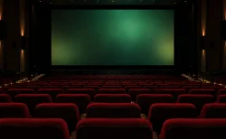暗転直前の映画館の大スクリーンと、後方席から見た空席の赤いシート