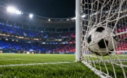 ナイター照明に照らされたスタジアムでゴールネットに収まったサッカーボール