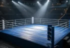 スポットライトに照らされた無人のボクシングリングと青いコーナーポスト