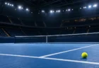 照明に照らされた無人の屋内アリーナの青いテニスコートとネット、黄色いテニスボール