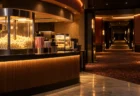 暖色の照明がともる夜の映画館ロビーと、無人のポップコーン売り場