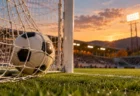 夕暮れのサッカースタジアムでゴールネットに入ったボール