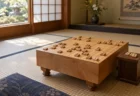 和室の畳の上に置かれた木製の将棋盤と駒台、盤上に並ぶ将棋の駒