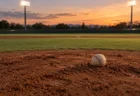 夕暮れの野球場のマウンドに置かれた白い硬式球とナイター照明
