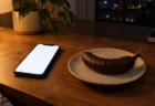 夜の部屋の机の上で光るスマートフォンとチョコレートがけのバナナ