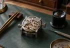 時計職人の作業台に置かれた懐中時計のムーブメントとルーペ、ピンセット