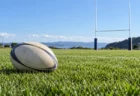 晴れた日の天然芝のラグビー場に置かれたラグビーボールとゴールポスト