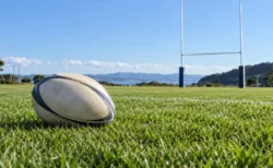 晴れた日の天然芝のラグビー場に置かれたラグビーボールとゴールポスト