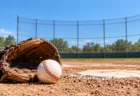 野球場のホームベース脇に置かれたミットと硬式野球ボール